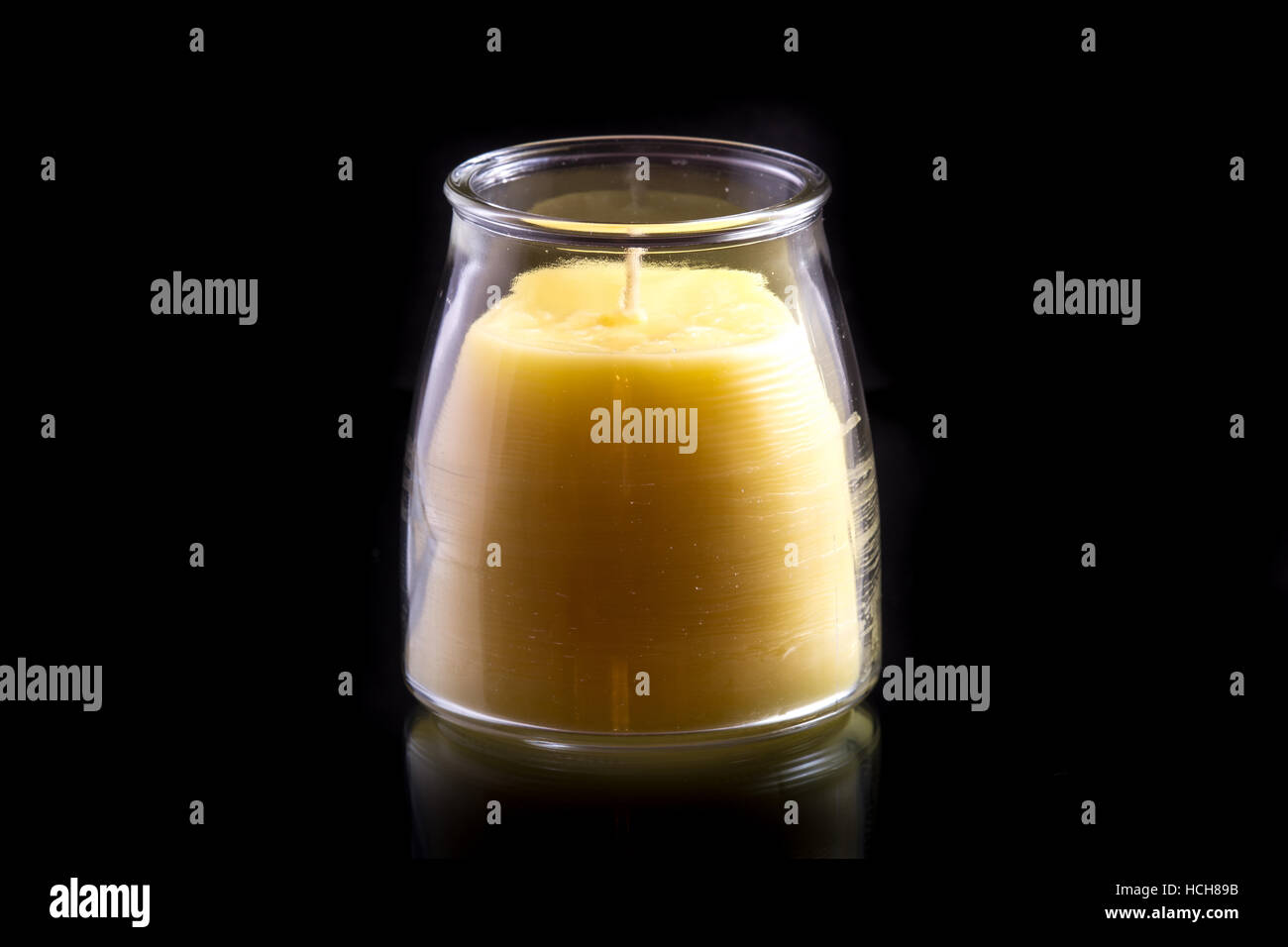 Bienenwachs Kerzen (unbeleuchtet) in einem Glas auf einem schwarzen Hintergrund mit einer subtilen Reflexion Stockfoto