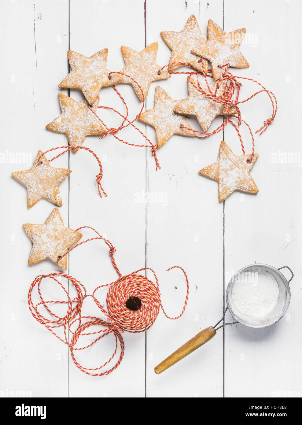 Hausgemachter Lebkuchen Weihnachtsstern geformt Plätzchen mit Puderzucker Sieb und rot Dekoration Seil über weißem Holz Hintergrund, Draufsicht, Kopie spa Stockfoto