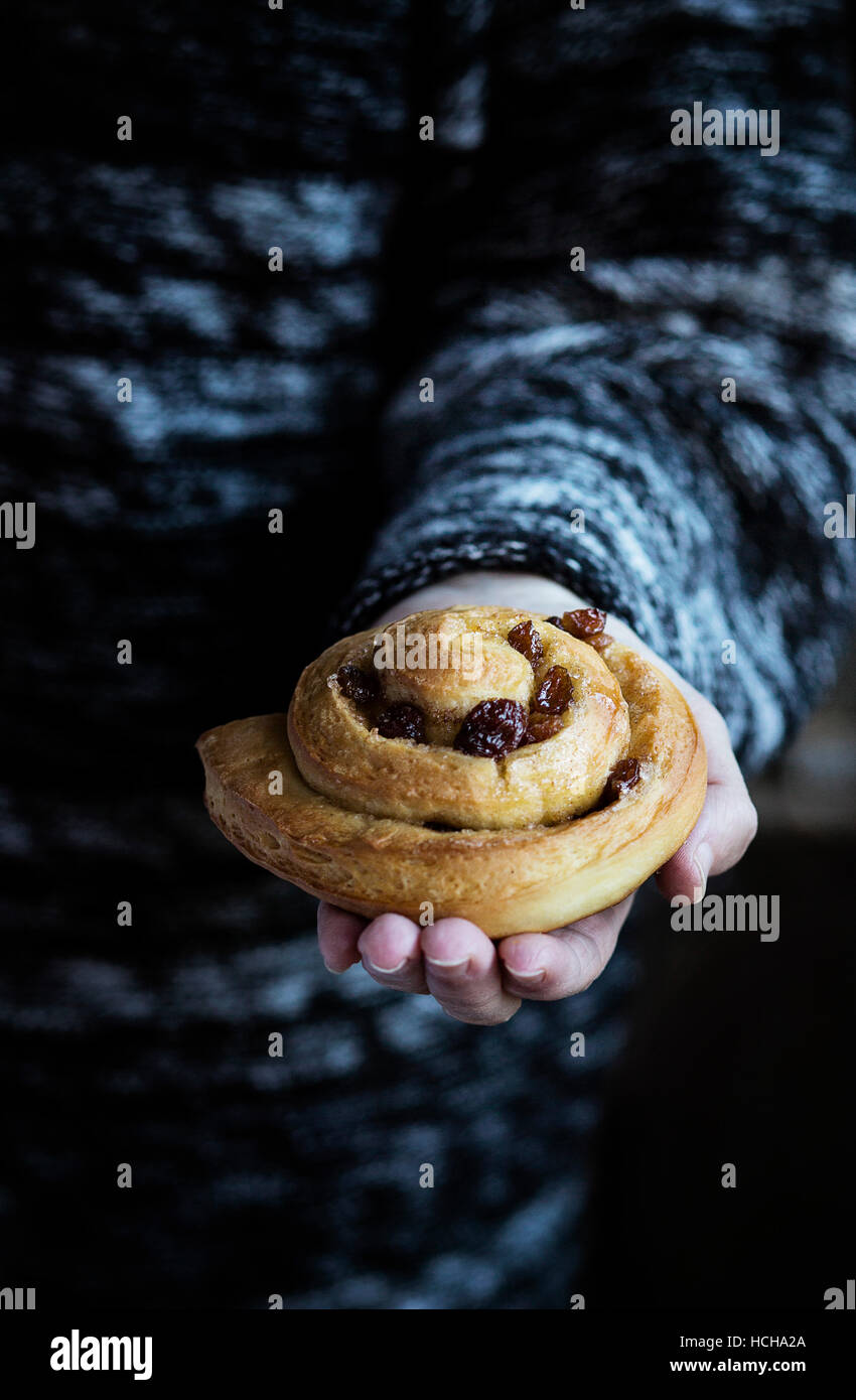 Frau mit einem hausgemachten Zimtbrötchen Stockfoto