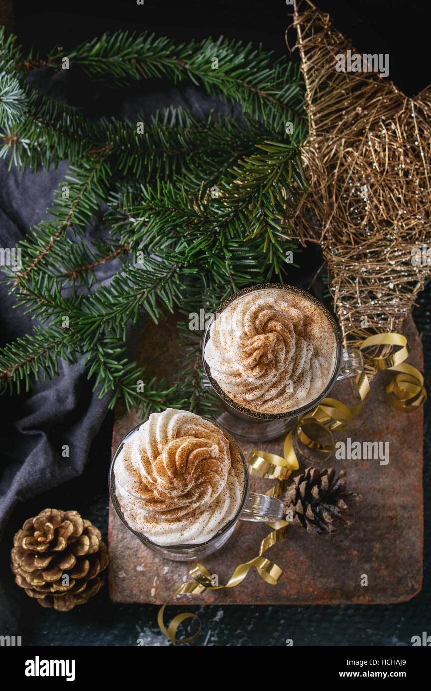 Kürbis würzig Latte mit Sahne und Zimt in zwei Gläser stehend auf Lehm-Board mit Textil- und Weihnachten Dekoration Tanne Baum andere dunkel b Stockfoto