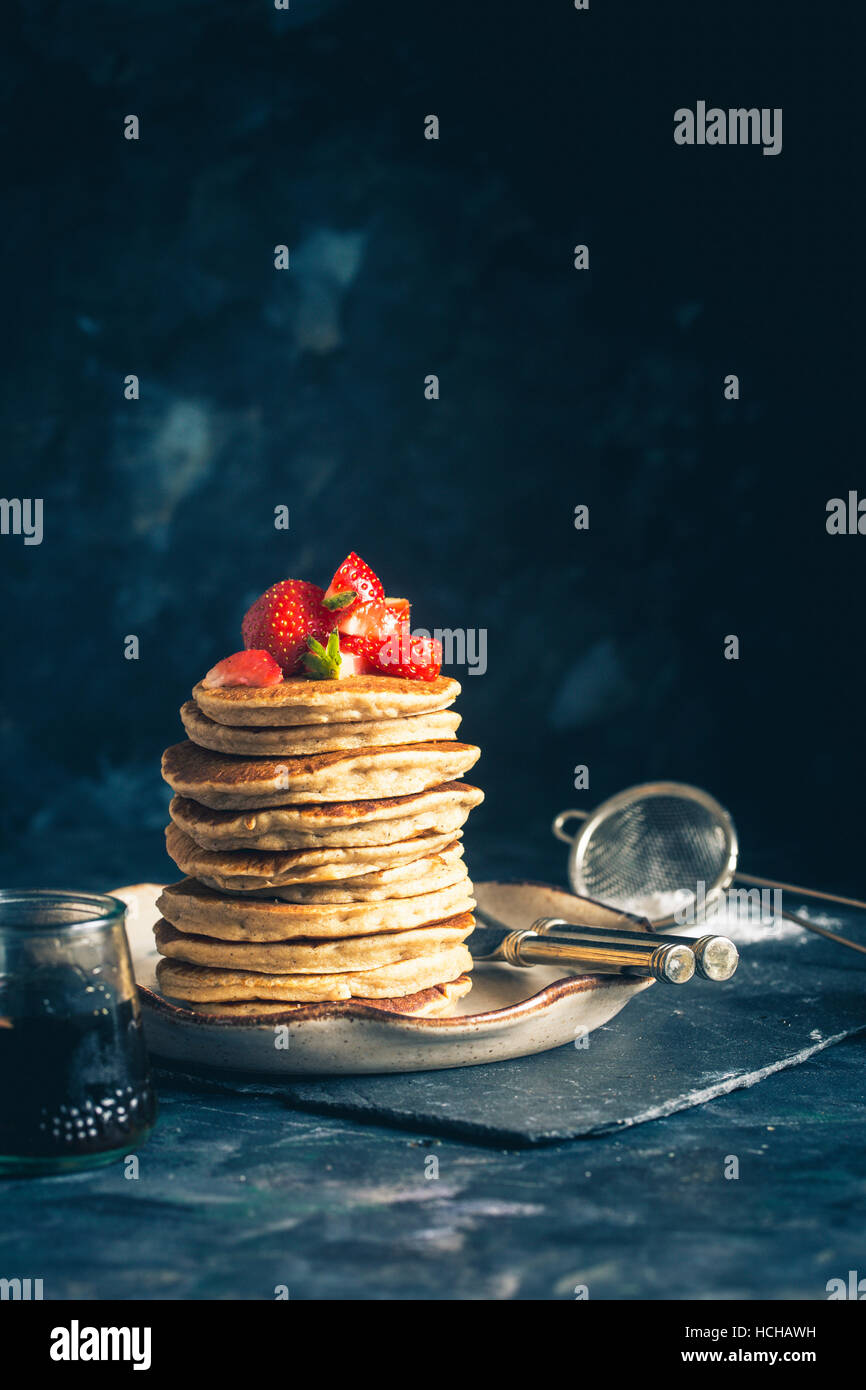 Stapel von Gluten-freie Hafer Mehl Pfannkuchen serviert mit gehackten Erdbeeren und Ahornsirup Stockfoto