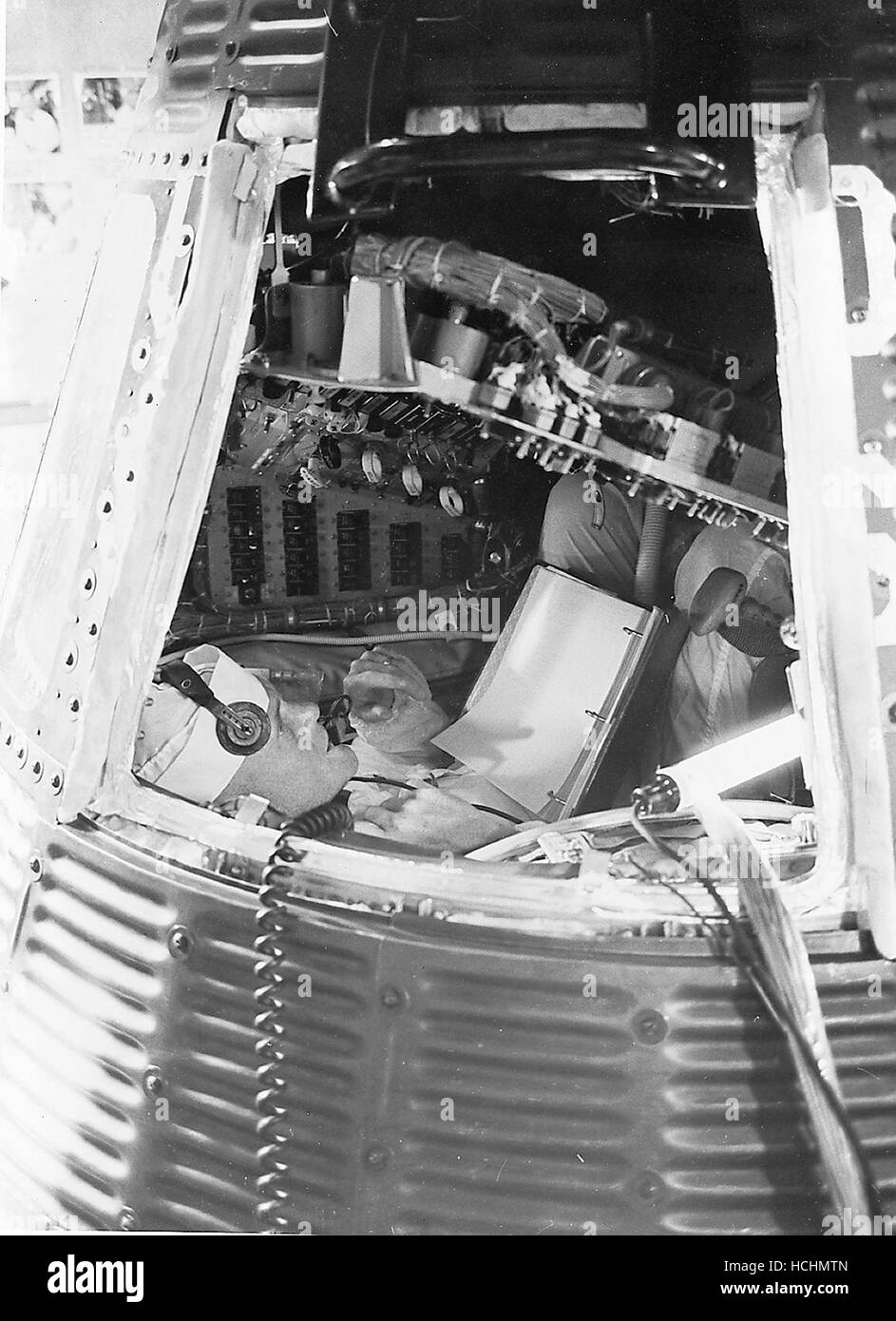 Astronaut John H. Glenn Jr., backup Astronaut für MR-4, prüft das Innere eines Mercury-Raumschiffs auf Pad 5 im Juli 1961. Er prüft Material auf der Checkliste, die er gegen die Konsolen vor ihm hält. Credit: NASA über CNP /MediaPunch Stockfoto