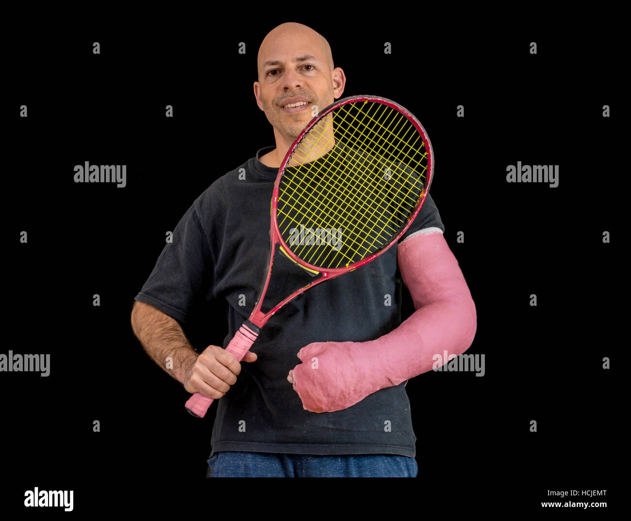 Junger Mann hält einen Tennisschläger nach seinem Handgelenk zu brechen, in  einem Tennis-Spiel, sporting einen passenden hellrot arm Cast, isoliert auf  schwarz Stockfotografie - Alamy