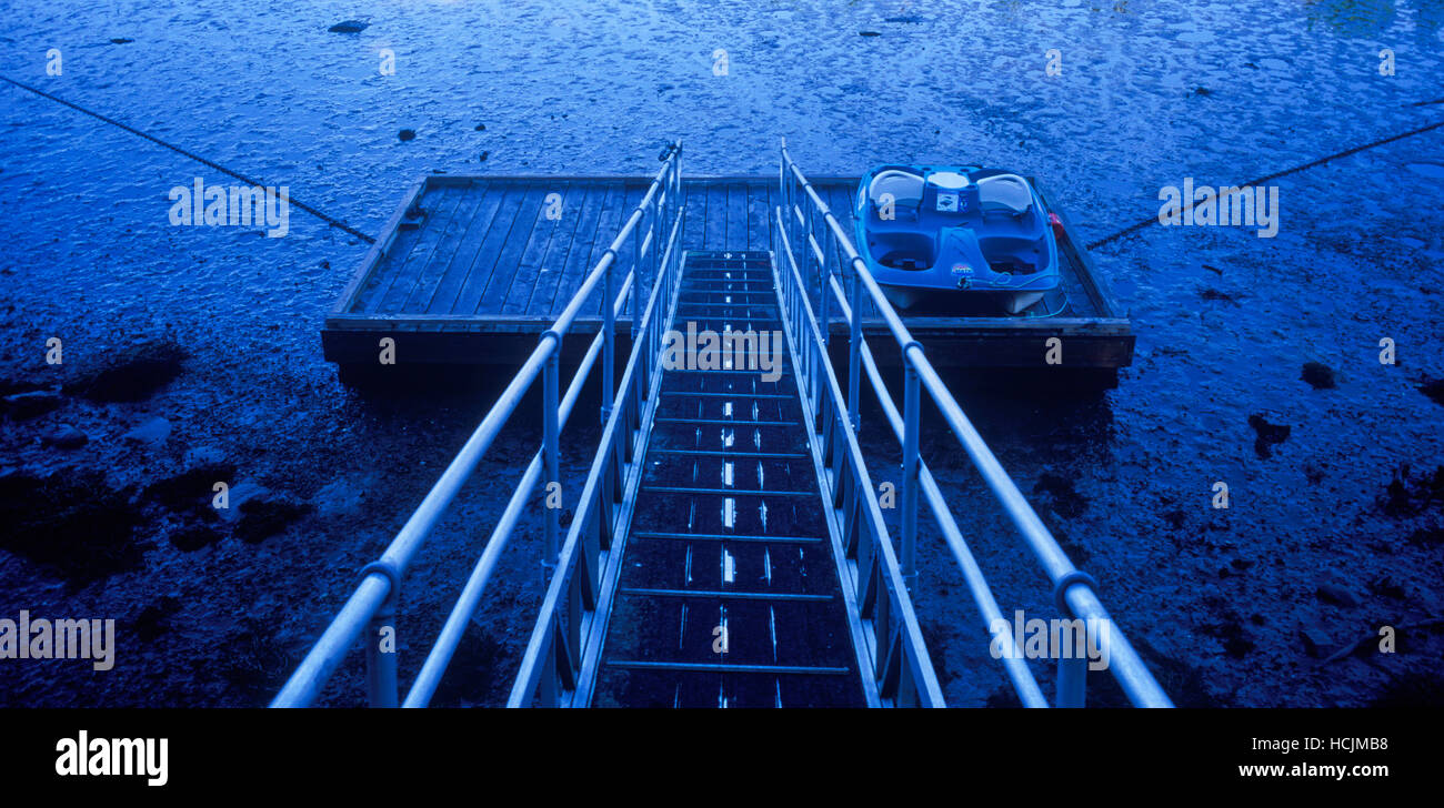 Ein kleines Dock sitzt auf dem schlammigen Boden der Bucht bei Ebbe in Maine. Stockfoto