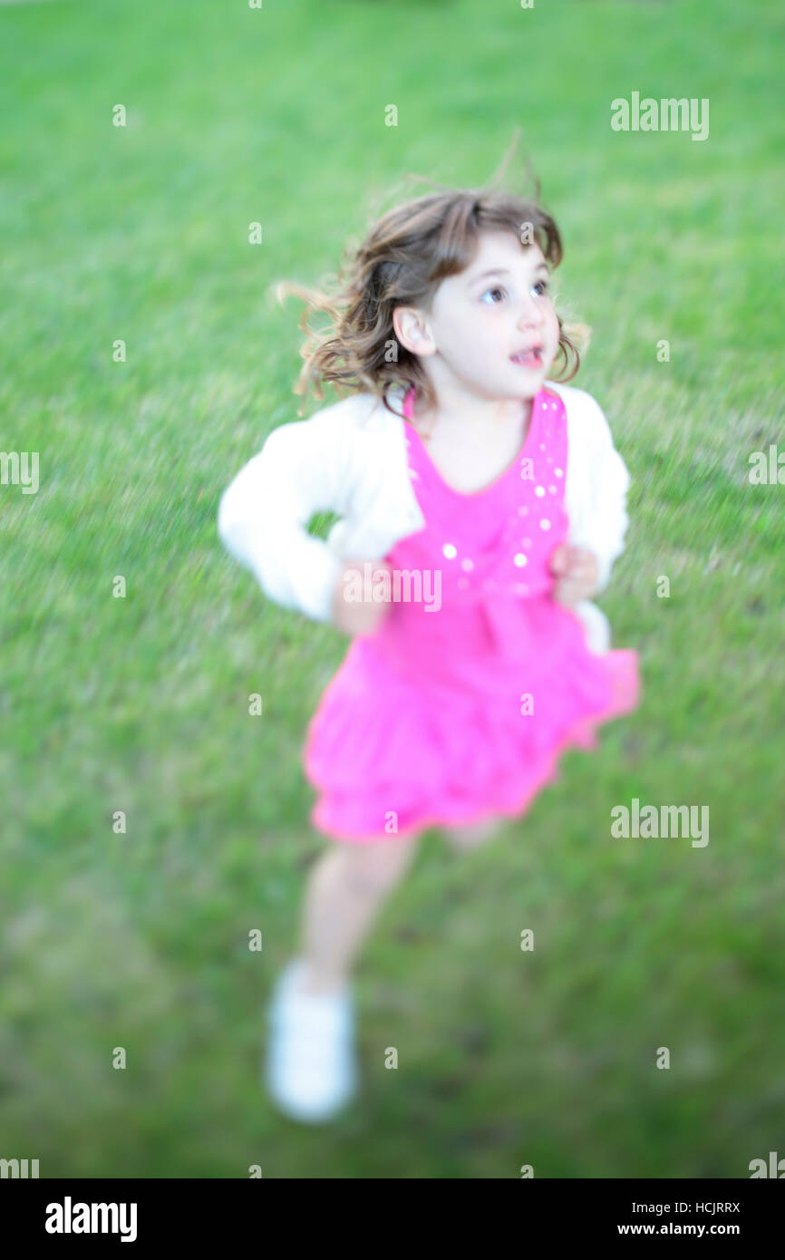 Mädchen, Alter 3 Jahre 8 Monate, läuft auf dem Rasen. Stockfoto