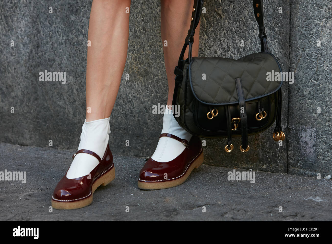 Frau mit dunklen roten Schuhen und Tasche mit goldenen Ringen vor Salvatore Ferragamo Modenschau, Milan Fashion Week Streetstyle. Stockfoto
