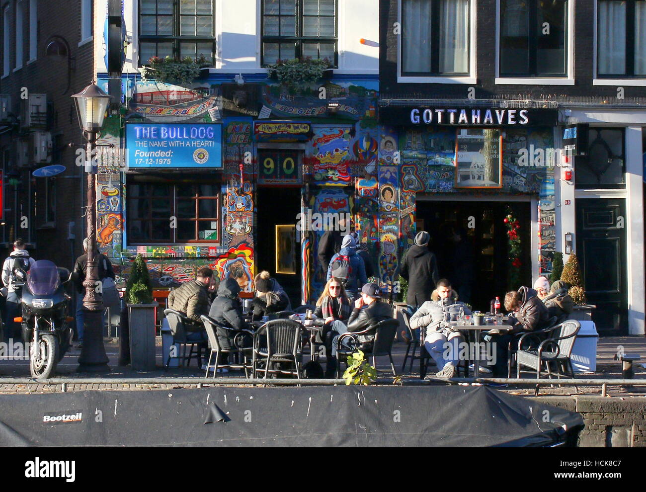 Personen auf Terrasse vor Coffeeshop Bulldog am Oudezijds Voorburgwal Kanal, Amsterdam, Niederlande Stockfoto