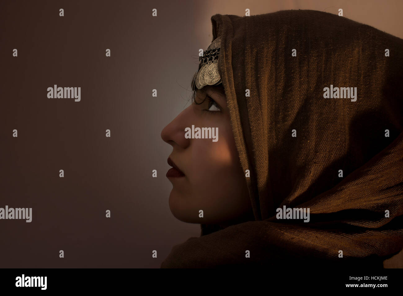 Porträt im Profil eines jungen Mädchens mit einem Schal und Münzschmuck auf dem Kopf als Symbol ihrer Keuschheit. Sie schaut sehend auf Stockfoto