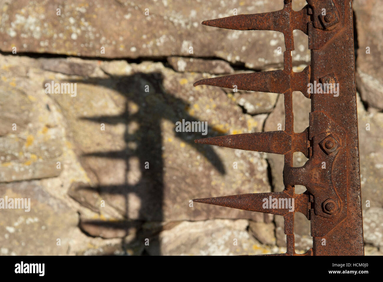 Rusty landwirtschaftliche Geräte gegen Steinmauer Stockfoto