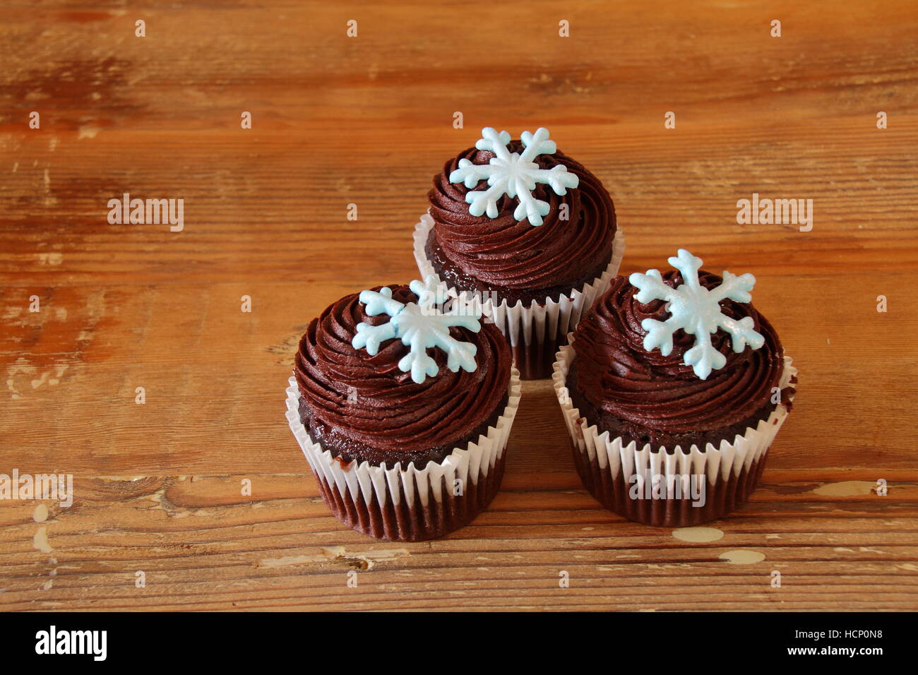 Schoko Cupcakes mit Schneeflocke Fräsen auf einer hölzernen Hintergrundbild mit Kopie Raum im Querformat isoliert Stockfoto