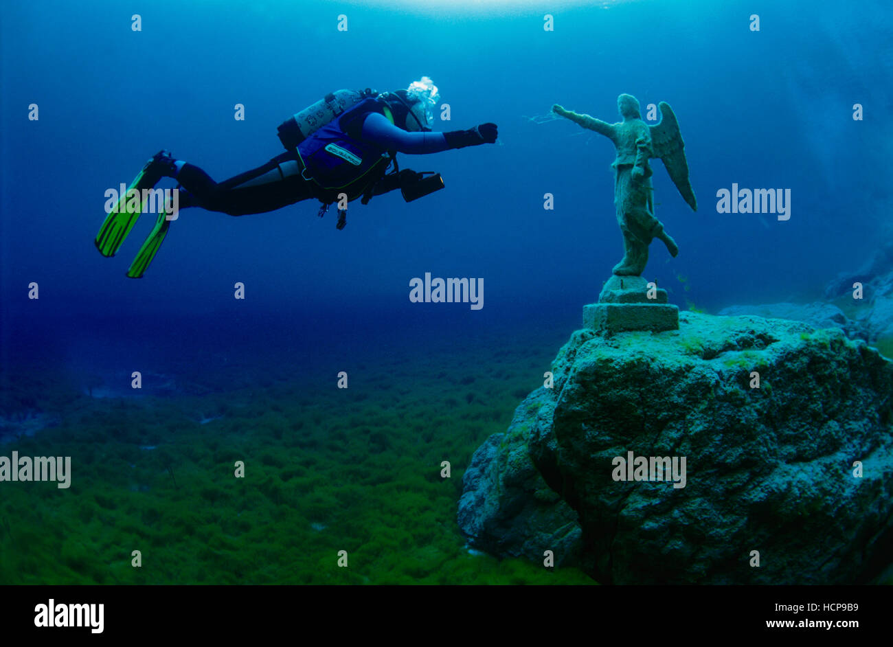 Taucher in einem Bergsee mit einer Statue eines Engels Stockfoto