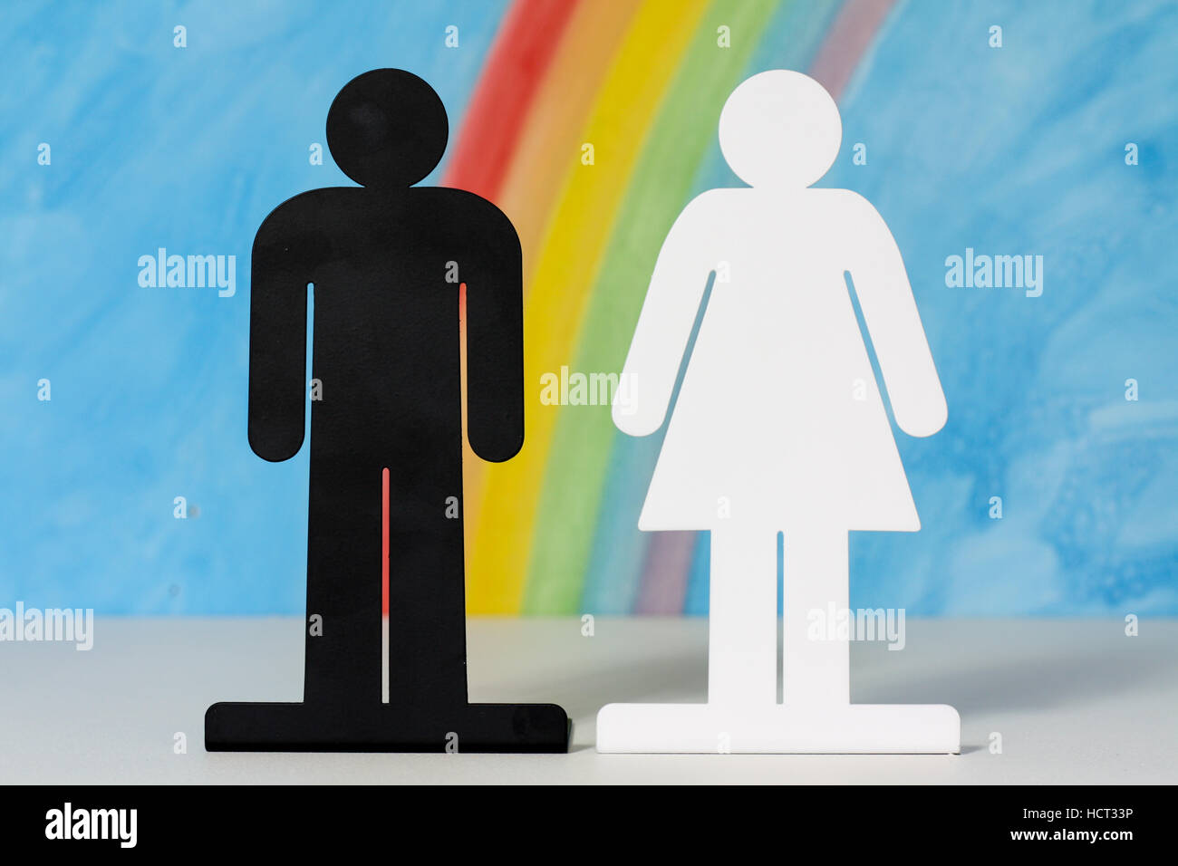Mann und Frau Symbole mit einem Regenbogen und blauer Himmel zur Veranschaulichung des Konzepts der Ehe, Beziehungen und Gleichstellung der Geschlechter. Stockfoto
