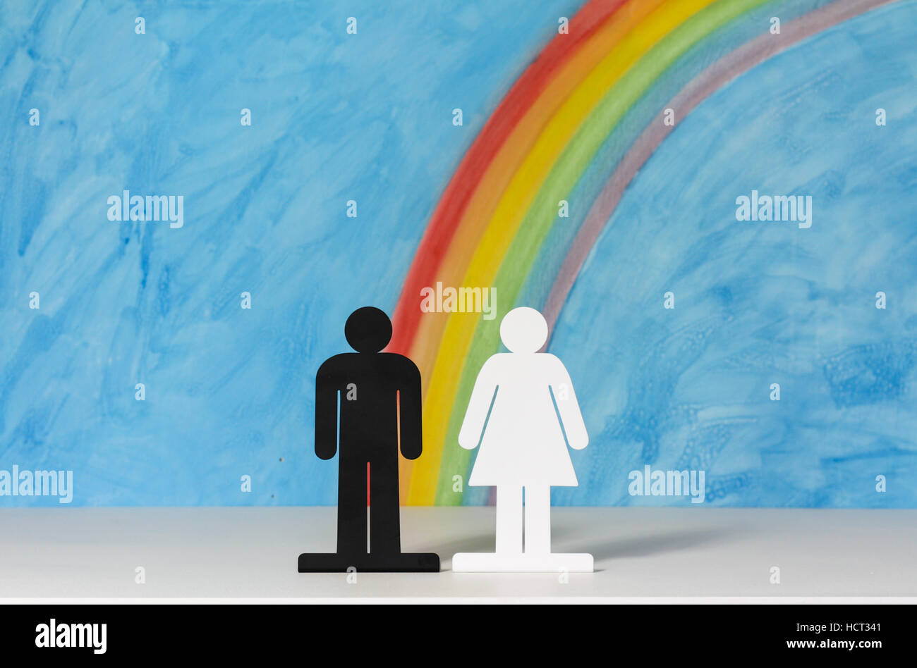Mann und Frau Symbole mit einem Regenbogen und blauer Himmel zur Veranschaulichung des Konzepts der Ehe, Beziehungen und Gleichstellung der Geschlechter. Stockfoto