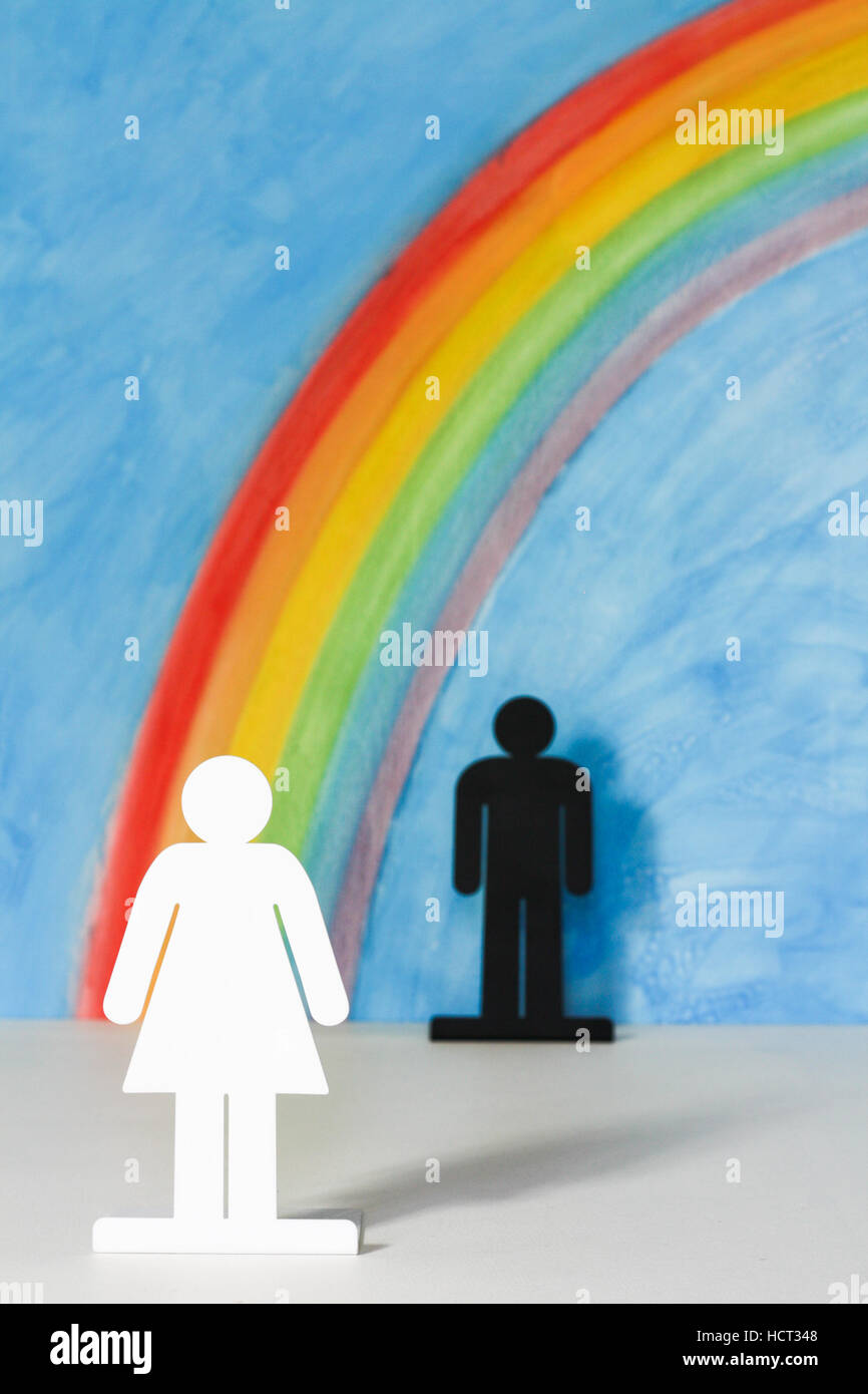 Mann und Frau Symbole mit einem Regenbogen und blauer Himmel zur Veranschaulichung des Konzepts der Gleichstellung der Geschlechter; Frau im Vordergrund. Stockfoto