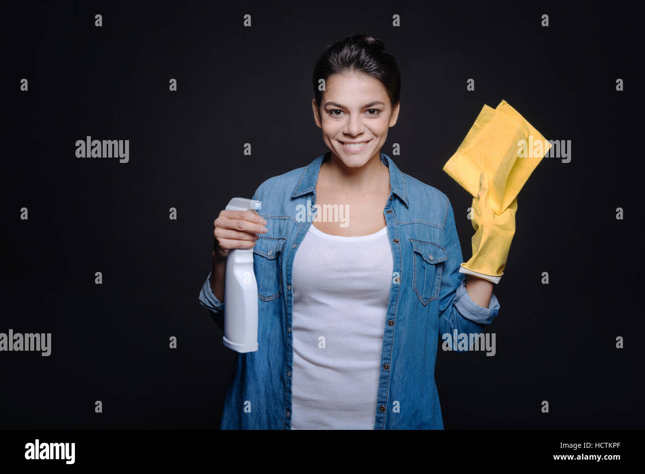Lächelnde junge Frau bereit, das Haus zu reinigen Stockfoto