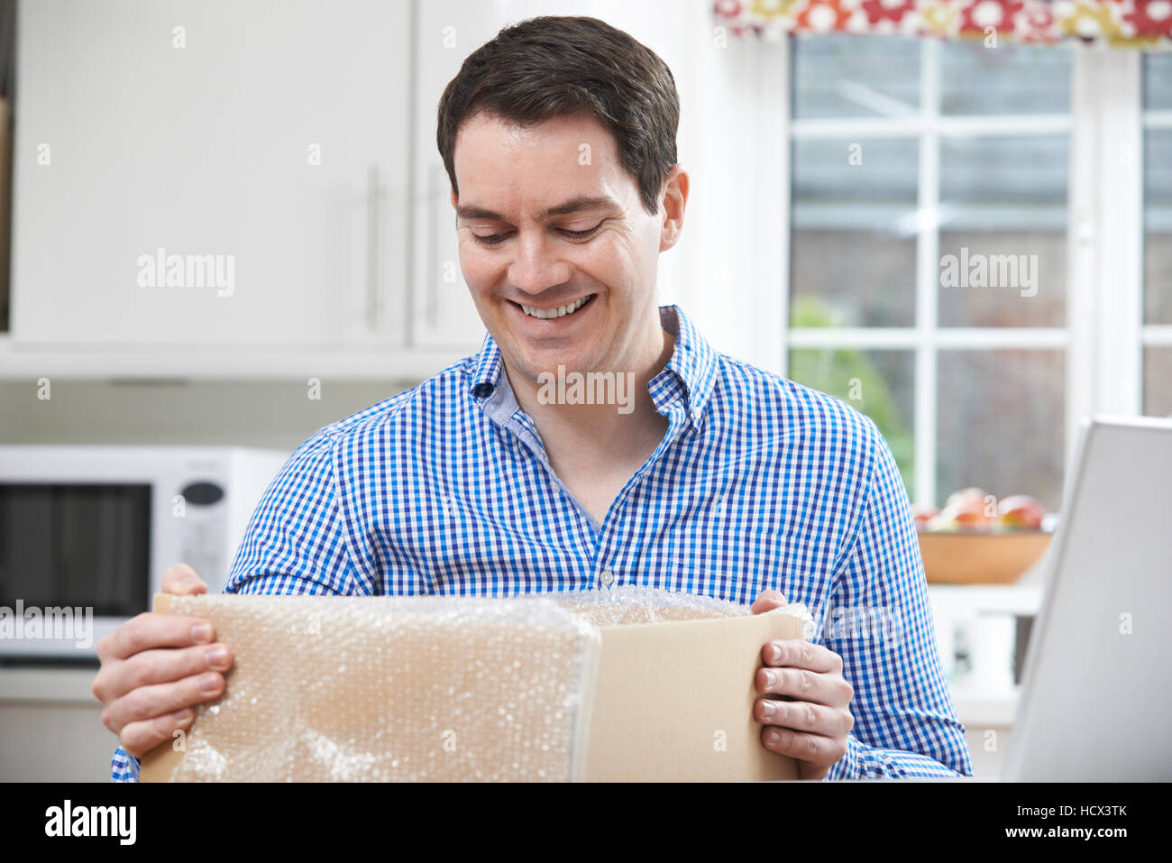 Glücklicher Mann Auspacken zu Hause Online-Kauf Stockfoto