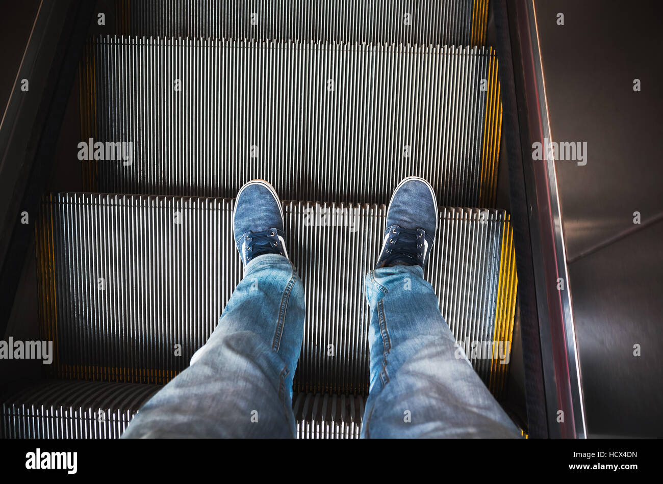 Männliche Füße in Jeans und Turnschuhen auf Rolltreppe Treppe Stockfoto