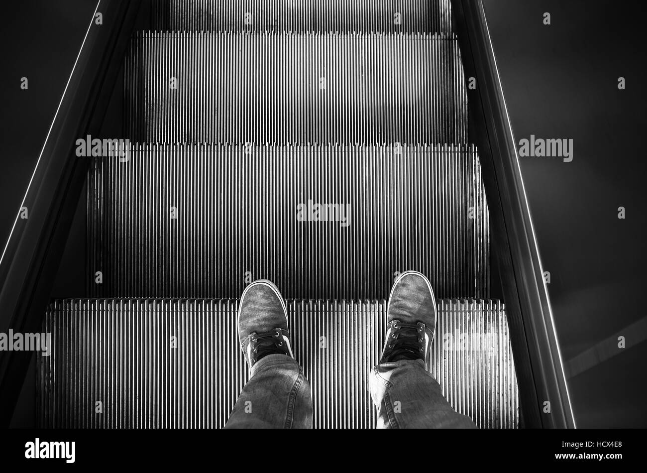 Männliche Füße in canvas Schuhe stehen auf der Rolltreppe Treppen, schwarz / weiß Stockfoto