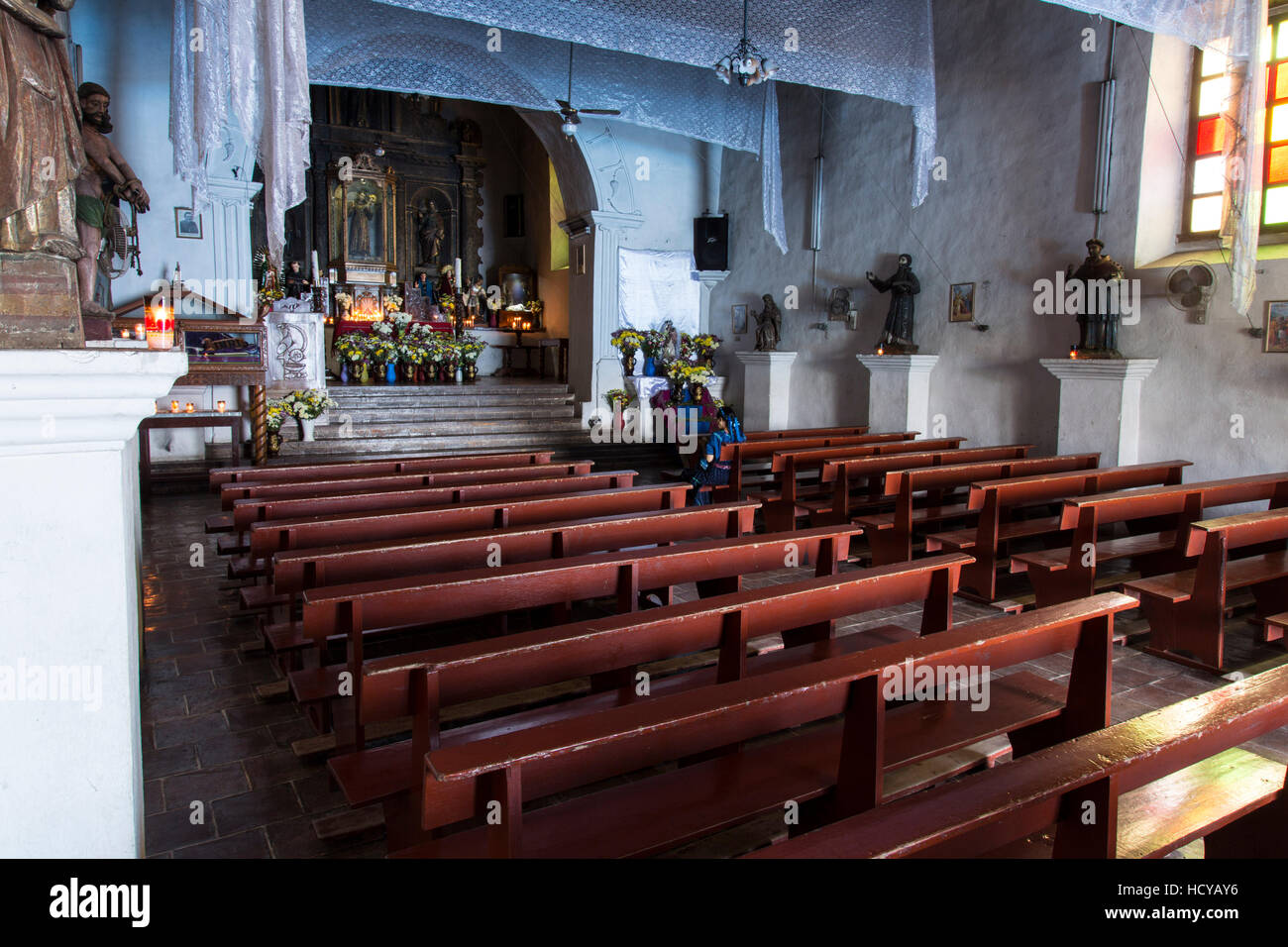 Innenraum des Hl. Antonius von Padua-Kirche in San Antonio Palopó, Guatemala, eine kleine katholische Kirche mit einer Frau in traditioneller Kleidung zu verehren. Stockfoto