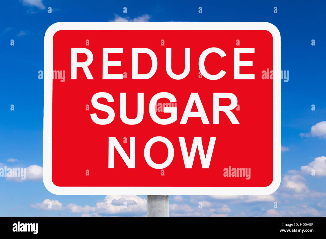 Roten und weißen Schild reduzieren Zucker nun vor einem blauen Himmel, symbol für das Gesundheitsrisiko oder die Gefahr von hohen Zuckerkonsum Stockfoto