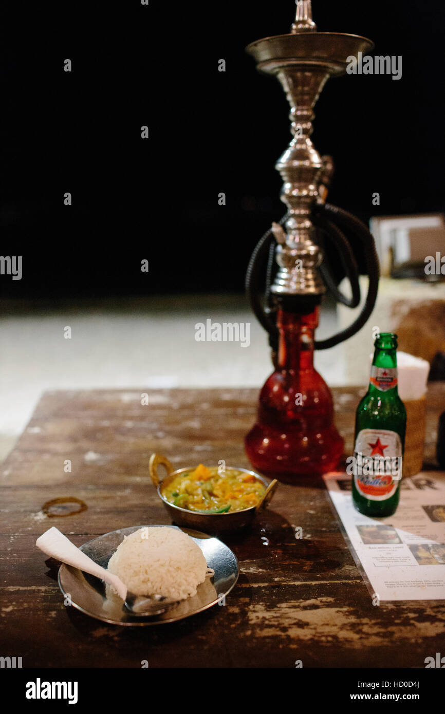 Ein indisches Curry Essen mit einer Flasche Indonesien Bintang Bier und einer Shisha Stockfoto