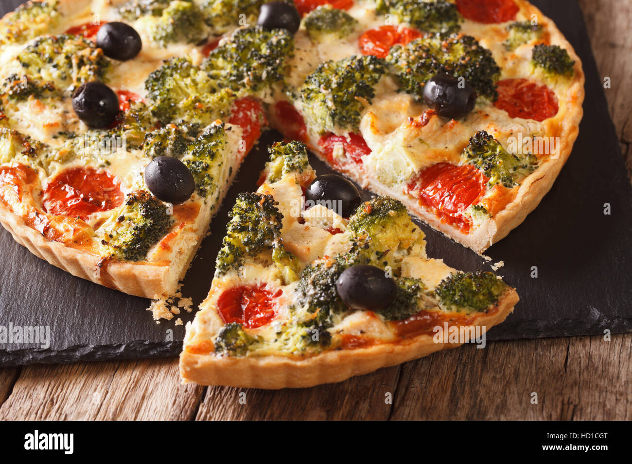In Scheiben geschnittene Quiche mit Hähnchen, Brokkoli, Tomaten und ...