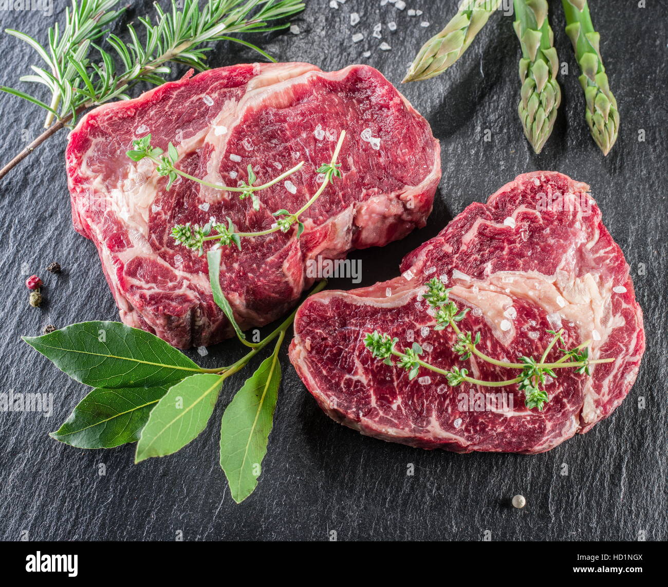 Rib-Eye-Steaks mit Gewürzen auf dem schwarzen Hintergrund. Stockfoto