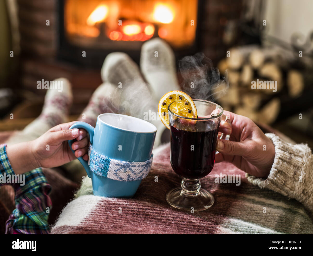 Wärmend und entspannend in der Nähe von Kamin. Mutter und Tochter mit den Tassen heißes Getränk vor Feuer. Stockfoto
