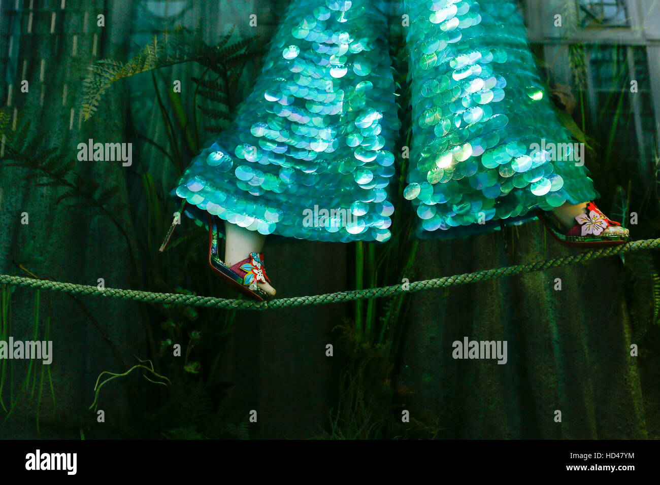 Eine Puppe in Pailletten-Hosen, die während der Feiertage in New York City auf einem Drahtseil spazieren gehen, symbolisiert das Gleichgewicht Stockfoto