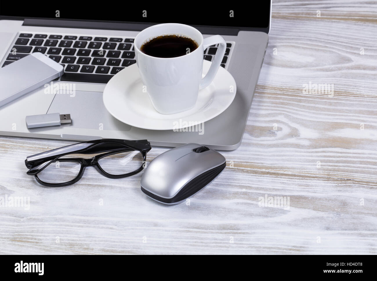 Nahaufnahme der Morgenkaffee auf Schreibtisch mit Laptop-Tastatur, USB-Stick, Lesebrille, und Handy. Stockfoto