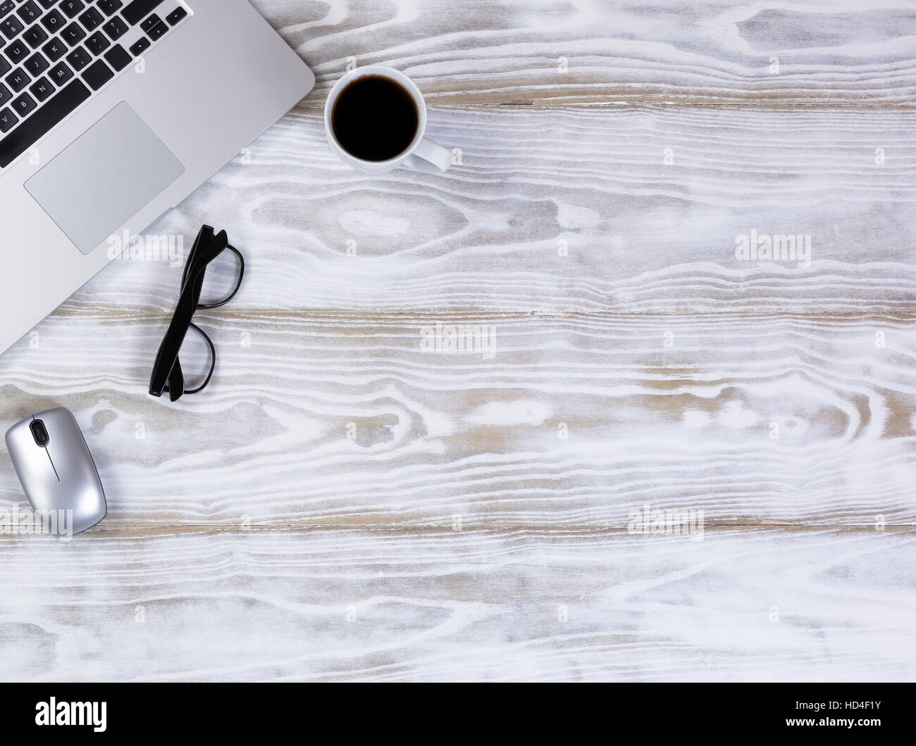 Draufsicht auf ein mobiles Büro-Arbeitsplatz mit Laptop-Tastatur, dunkel Kaffee, Lesebrille und kabellose Maus auf rustikale weiße Desktop. Stockfoto
