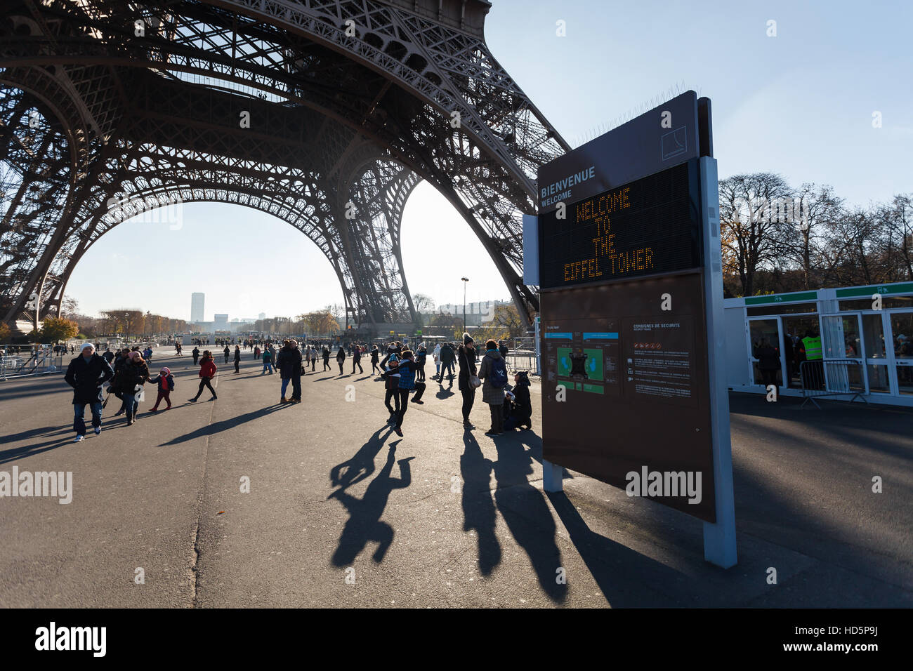 Board: "Willkommen auf dem Eiffelturm" gegen Eiffelturm und Touristen durch die Morgensonne leuchtet Stockfoto