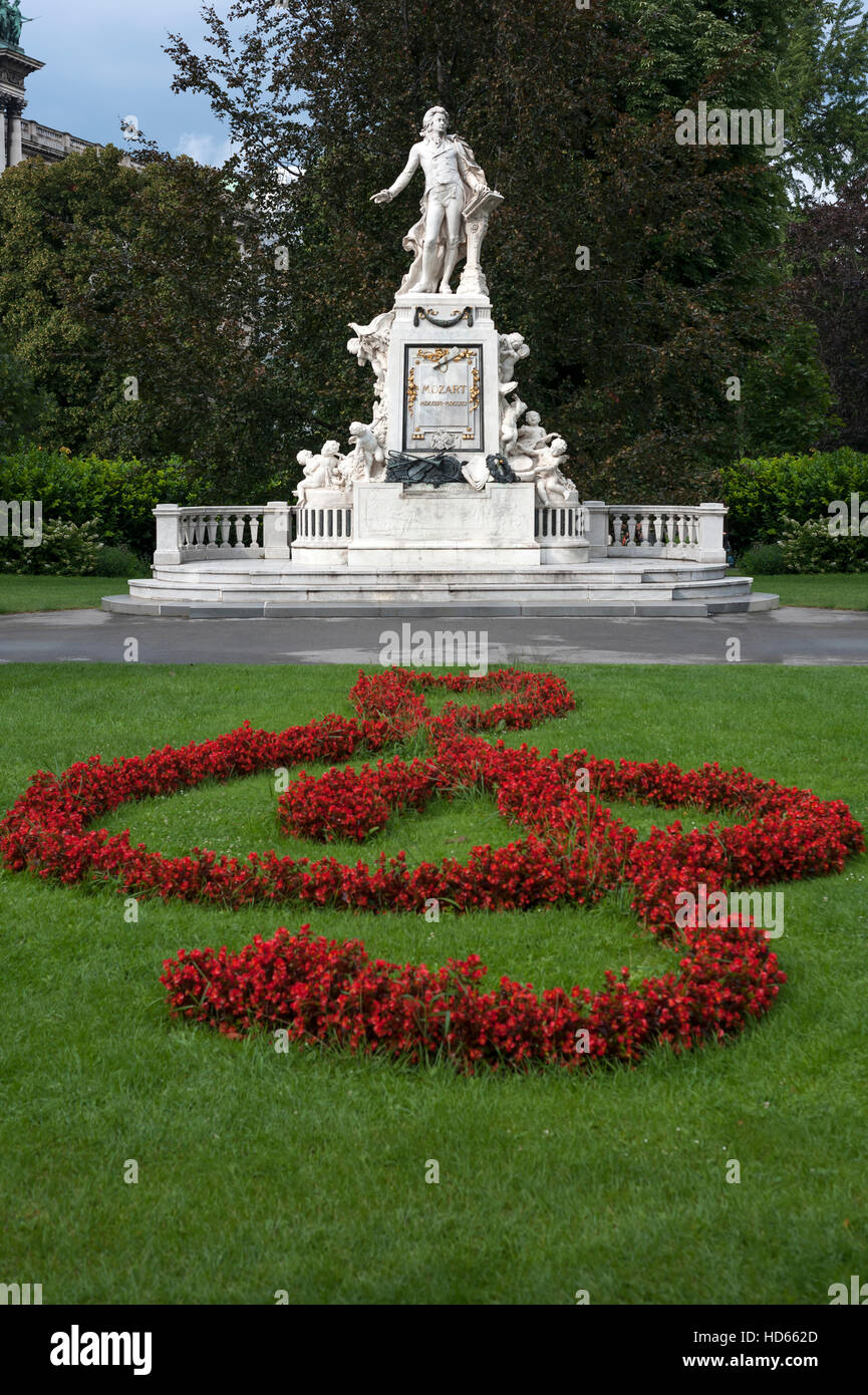 Rote Blumen arrangiert als Violin-Schlüssel mit Mozart-Denkmal, Schlossgarten, Wien, Österreich Stockfoto