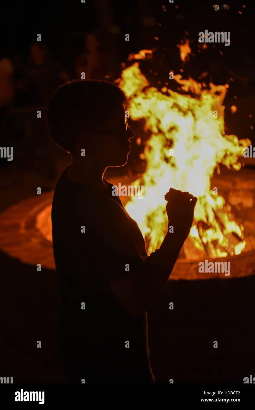 Eine Silhouette Junge wird fertig zu essen S'mores an einem Strand mit Lagerfeuer/Lagerfeuer - auch bekannt als ein Smores-kit Stockfoto