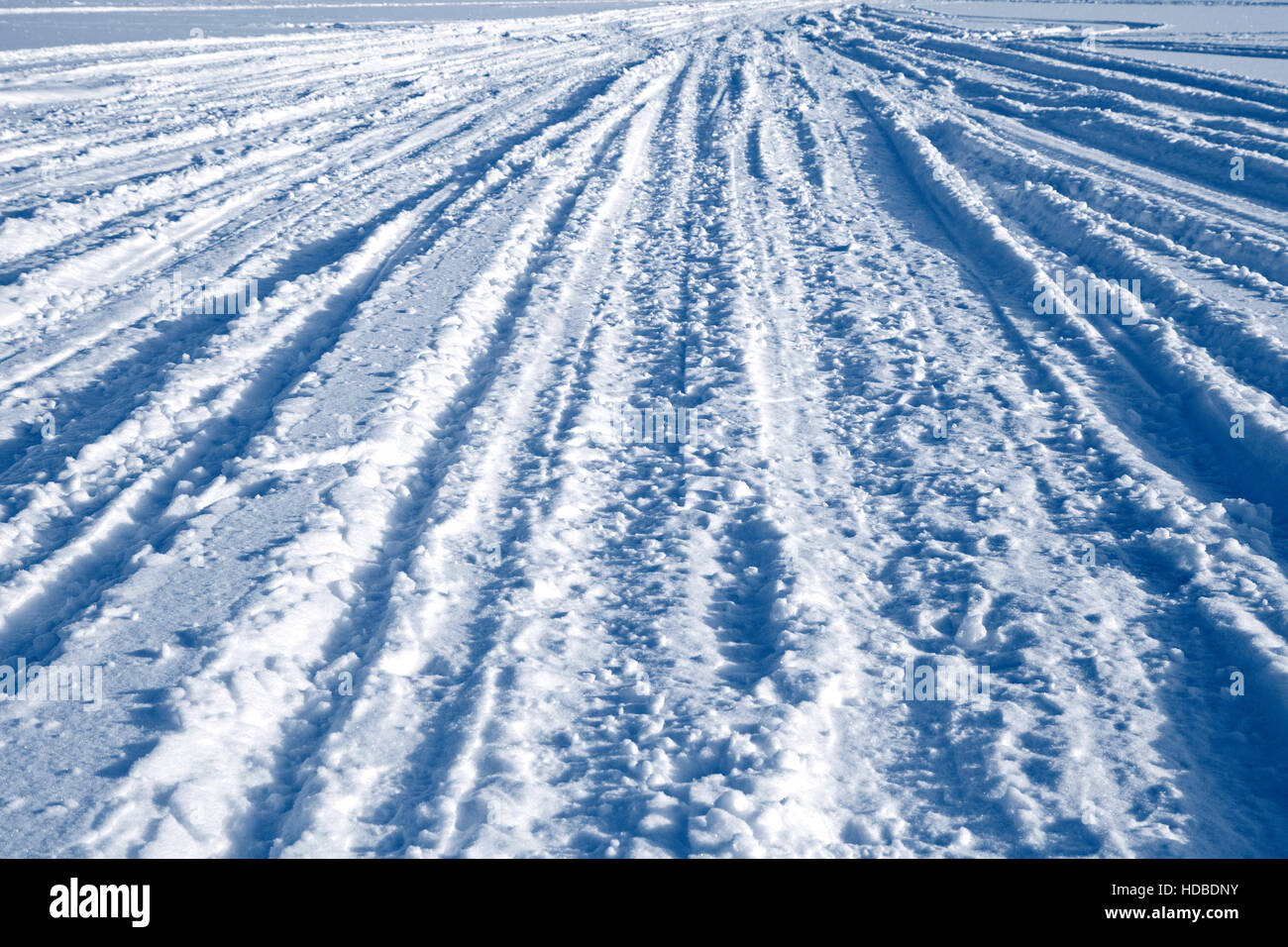 Viele Ski- und Auto-Spuren im Schnee Stockfoto