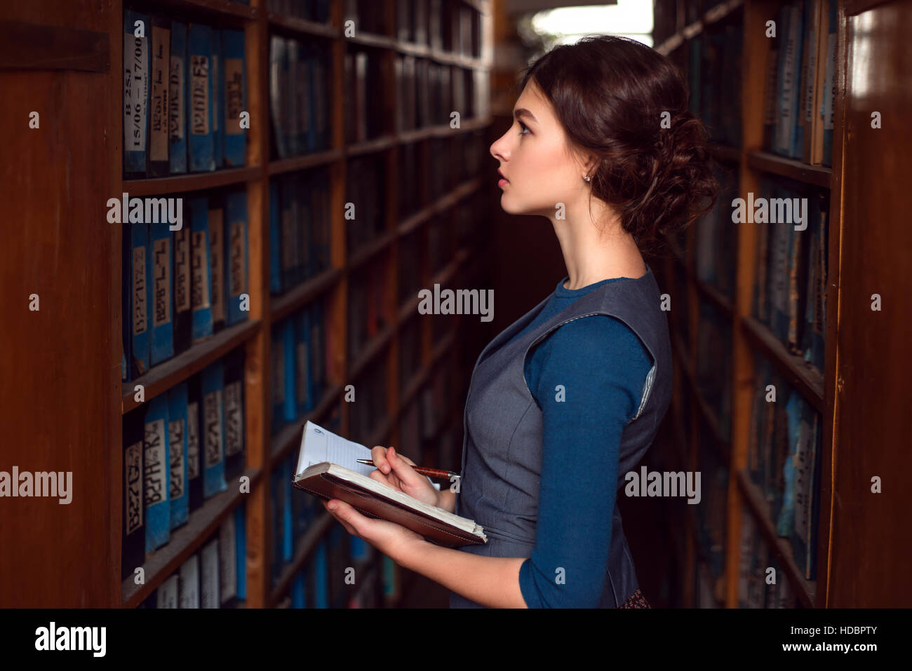 Junges Mädchen mit Notebook Lehrbuch in College-Bibliothek auswählen Stockfoto