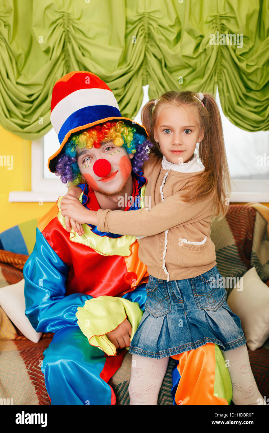 Kleines Mädchen umarmt einen fröhlichen Clown. Stockfoto