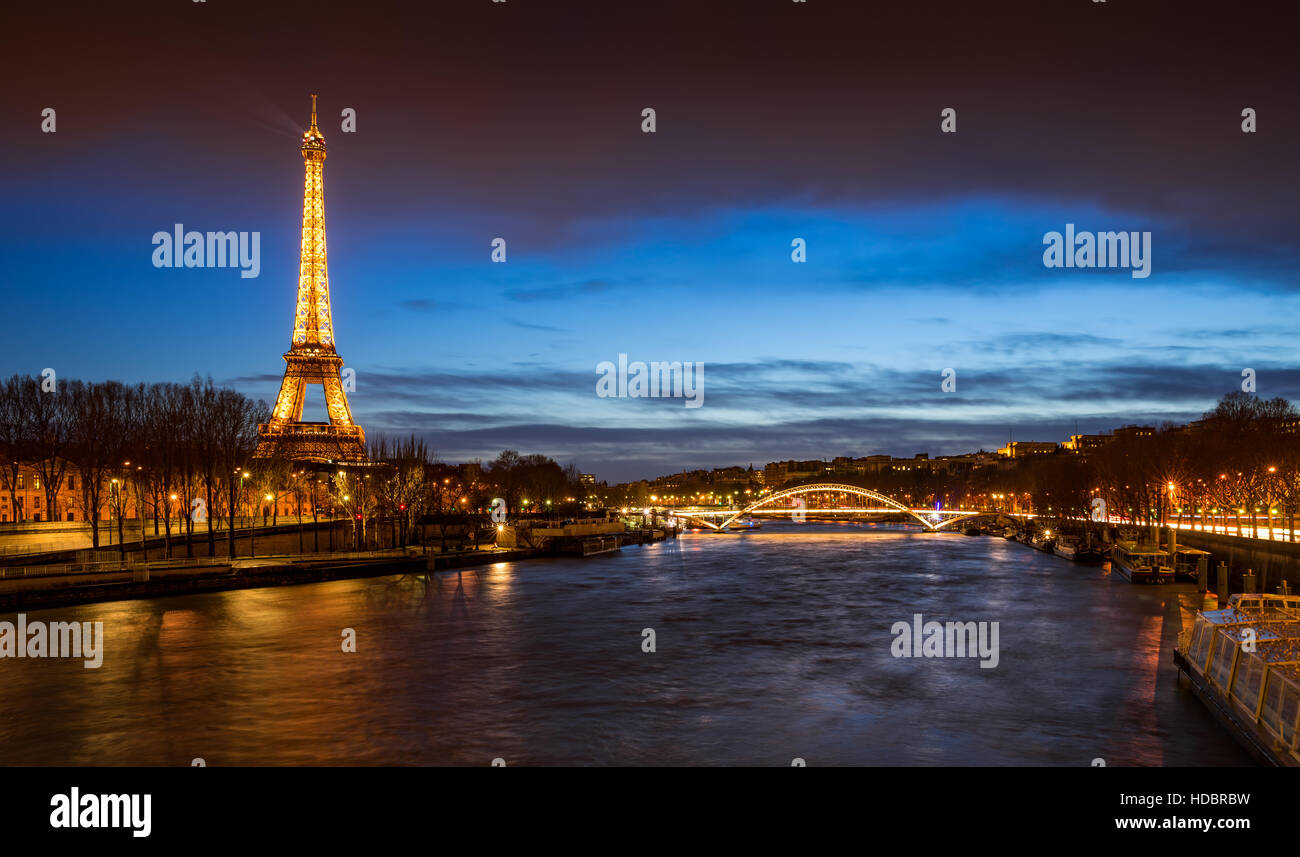 Der Eiffelturm in der Dämmerung mit den Ufern des Flusses Seine und die Passerelle Debilly beleuchtet. Paris, Frankreich Stockfoto