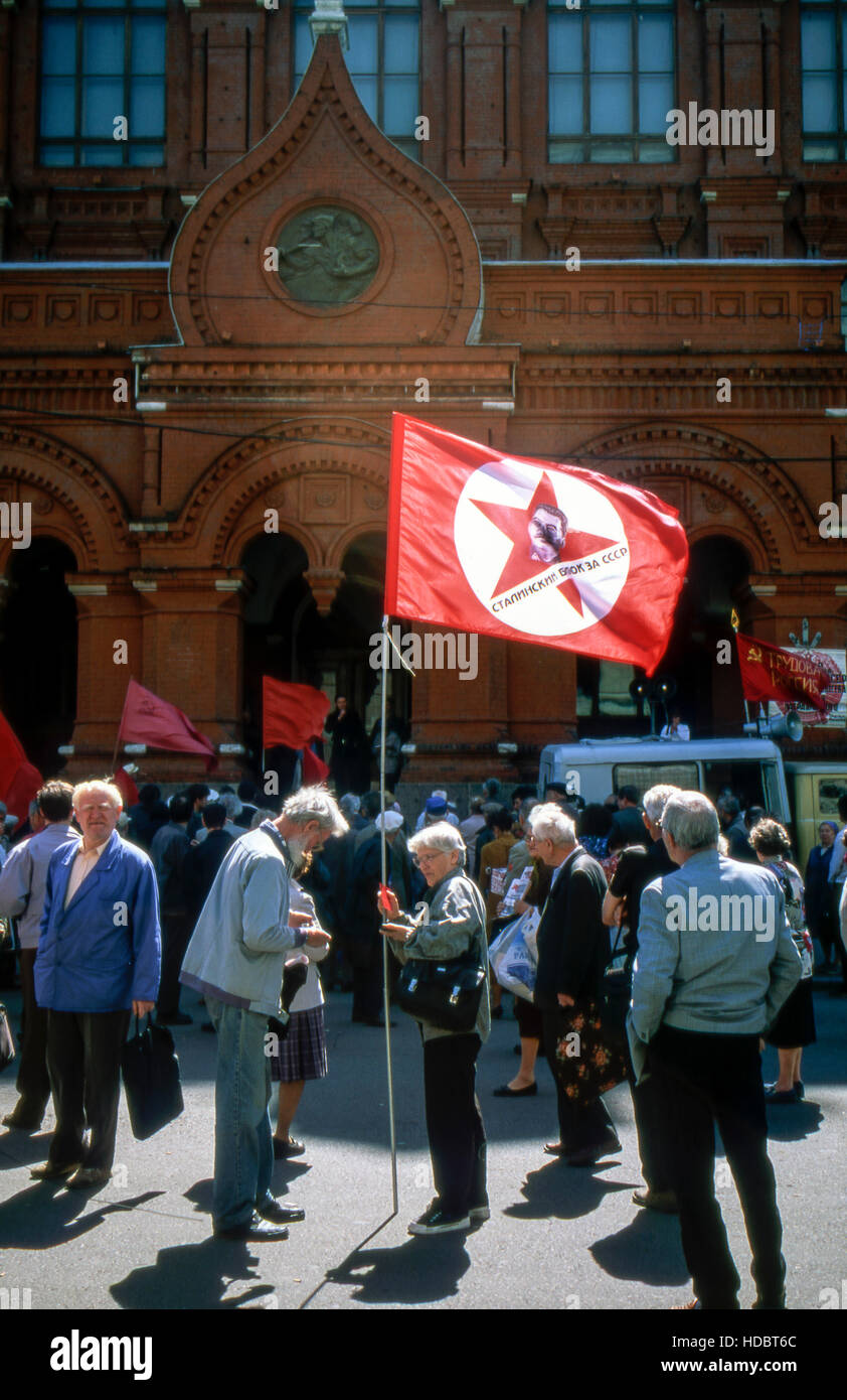 Kommunistische Demonstration in Moskau. Alte Dame hält eine Fahne mit Stalin-Porträt. Stockfoto