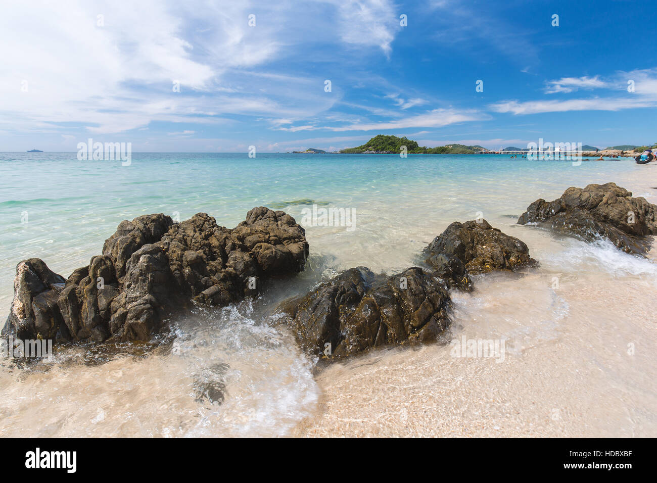 Klarem Wasser Strand des blauen Meeres mit schwarzem Rock und beweglichen Welle an sonnigen Tag in Thailand. Bewölkten blauen Himmel als Hintergrund. Stockfoto