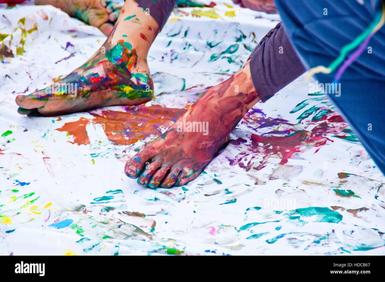 Kinder spielen, farbenfrohen Designs mit ihren Füßen in der bunten Tempera eingetaucht Stockfoto