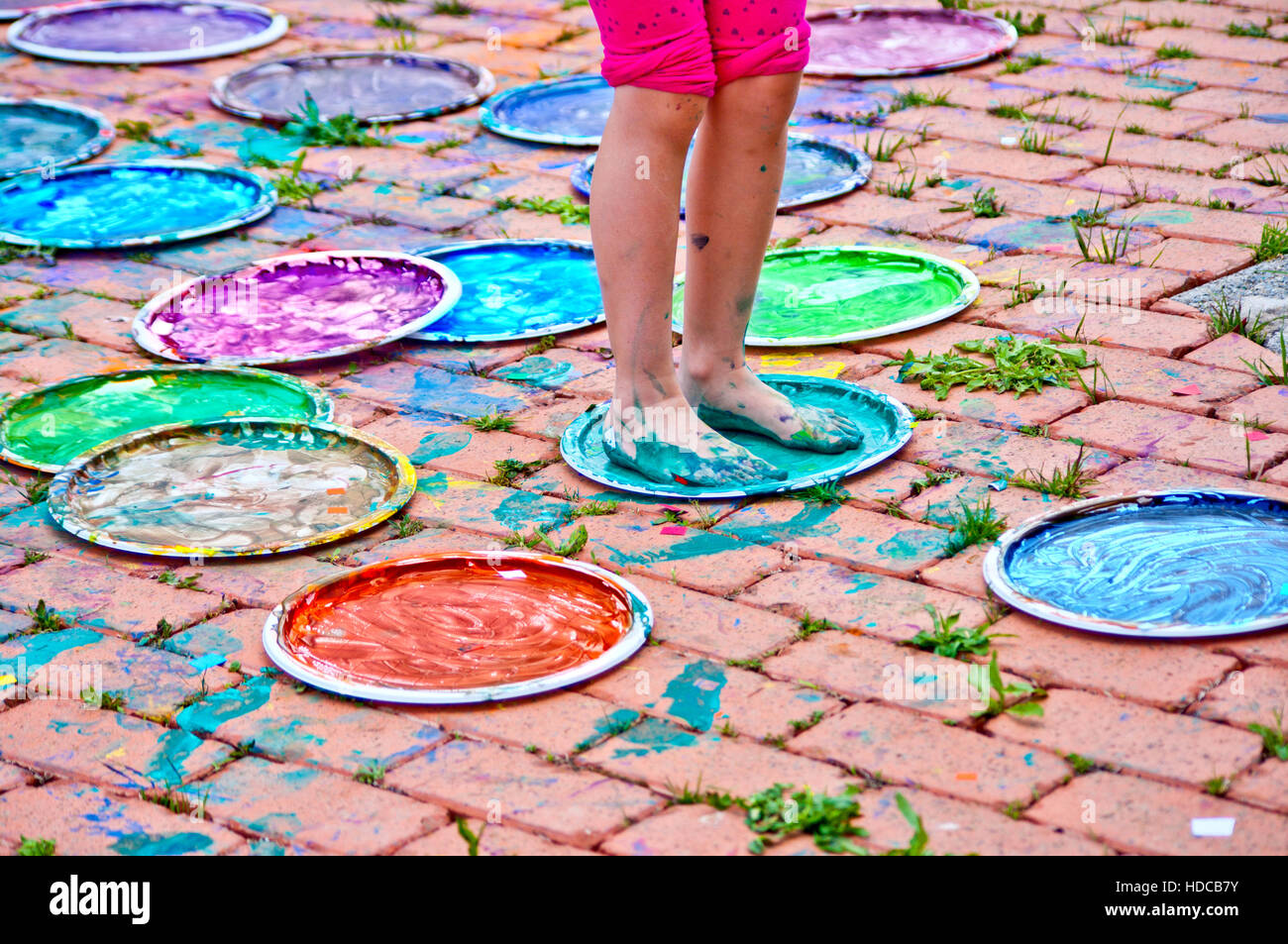 Kinder spielen, farbenfrohen Designs mit ihren Füßen in der bunten Tempera eingetaucht Stockfoto