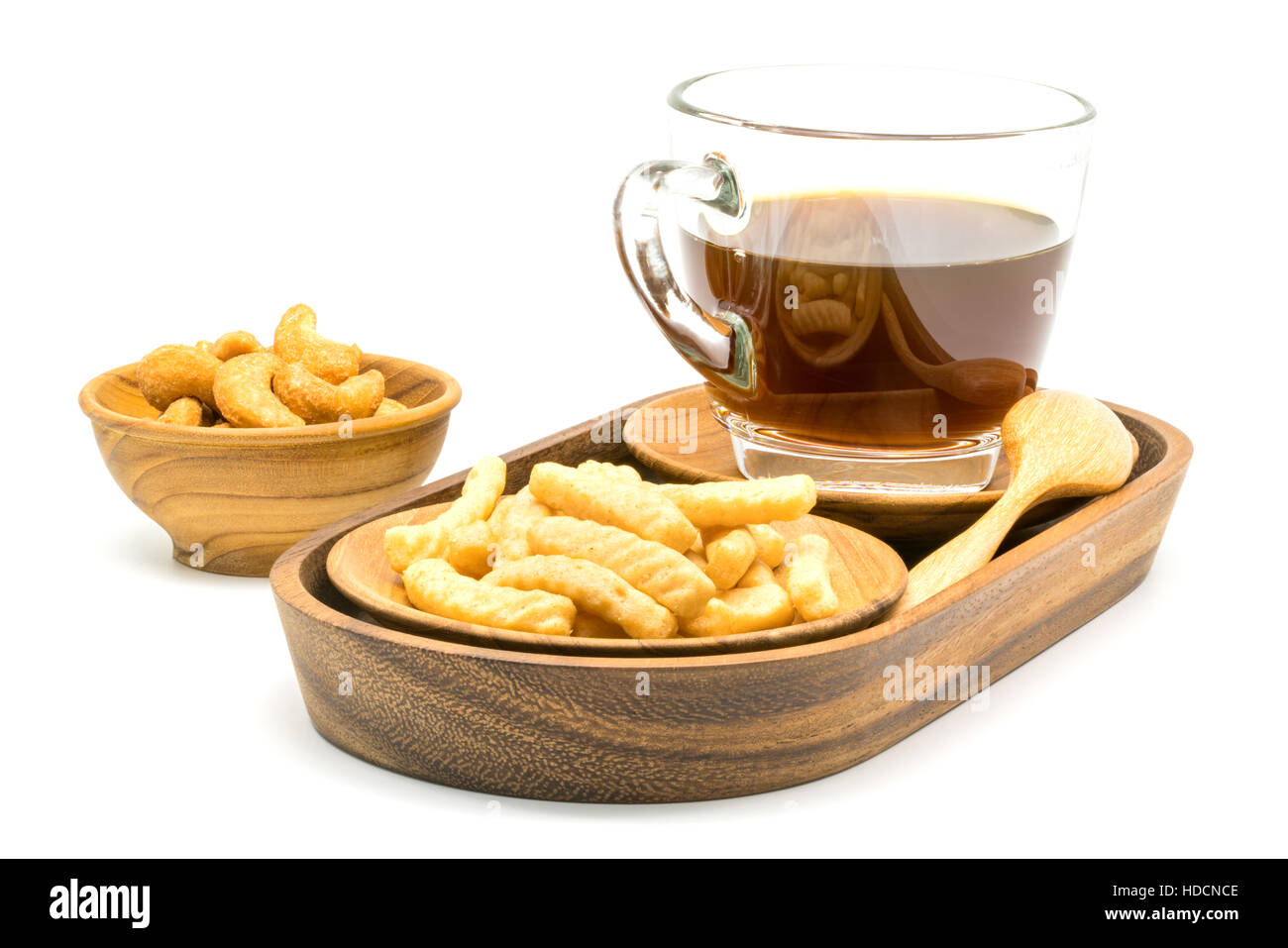 Garnelen-Cracker und eine Tasse schwarzen Kaffee in ein Holztablett mit salzigen Cashew-Nüssen in einer Holzschale auf weißem Hintergrund Stockfoto