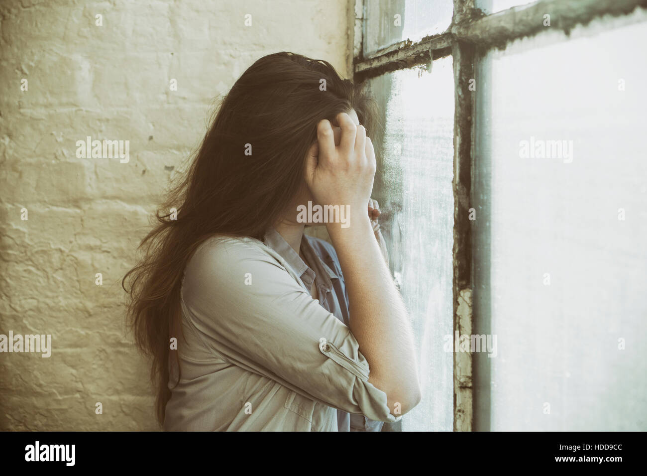 Depressive Frau Gesicht mit der Hand am Fenster versteckt Stockfoto