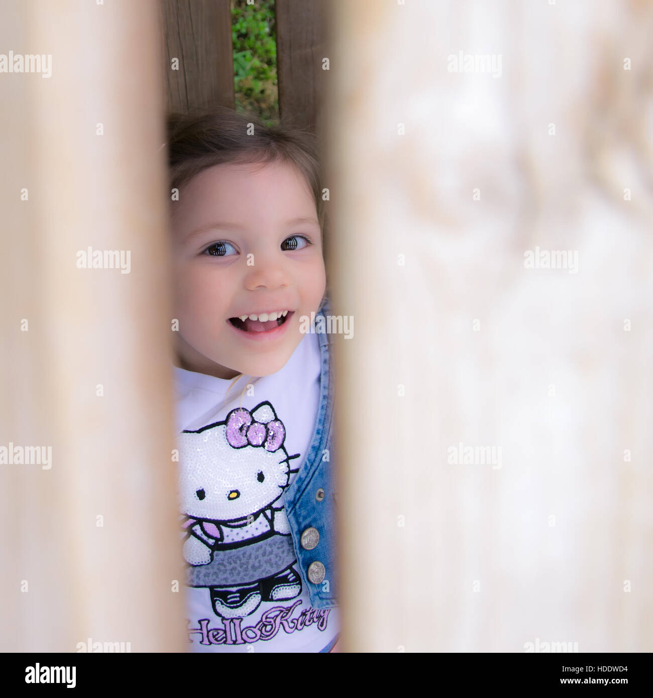 Verona, Italien - 29. März 2015: Kind mit Hello Kitty Shirt lacht versteckt hinter einem Holzzaun. Stockfoto