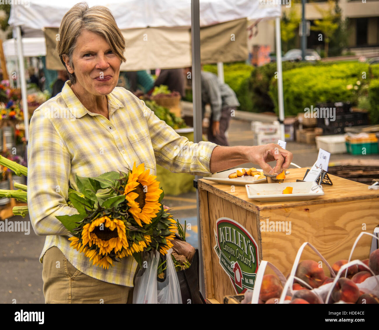 Boise Farmers Market, Pfirsiche Frau Probenahme frisch zum Verkauf. Die Innenstadt von Boise, Idaho Stockfoto
