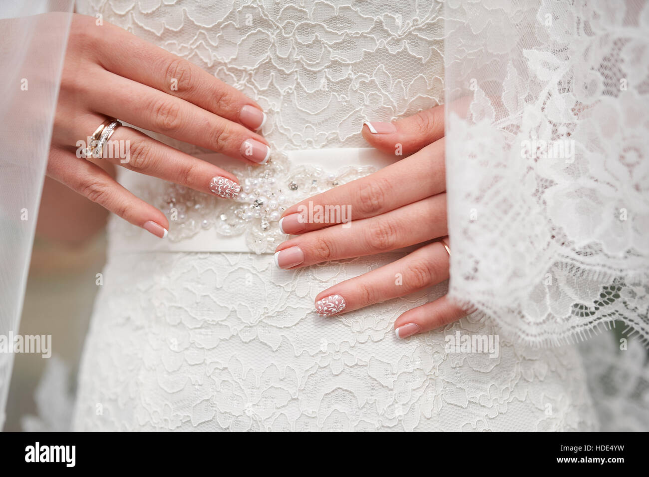 Hände der Braut mit einer Maniküre auf weißes Kleid, Nahaufnahme Stockfoto