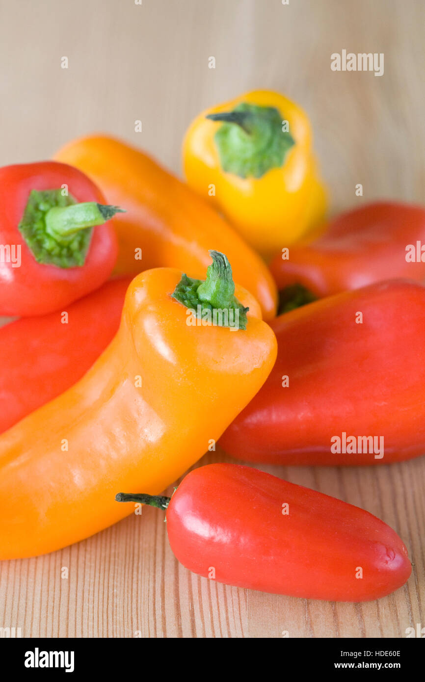 Ein Haufen bunter Mini-Paprika auf einem Holztisch. Stockfoto