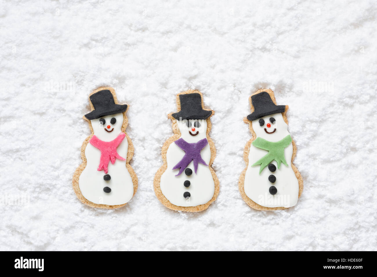 Drei hausgemachte Schneemänner Kekse auf einem verschneiten Hintergrund. Stockfoto