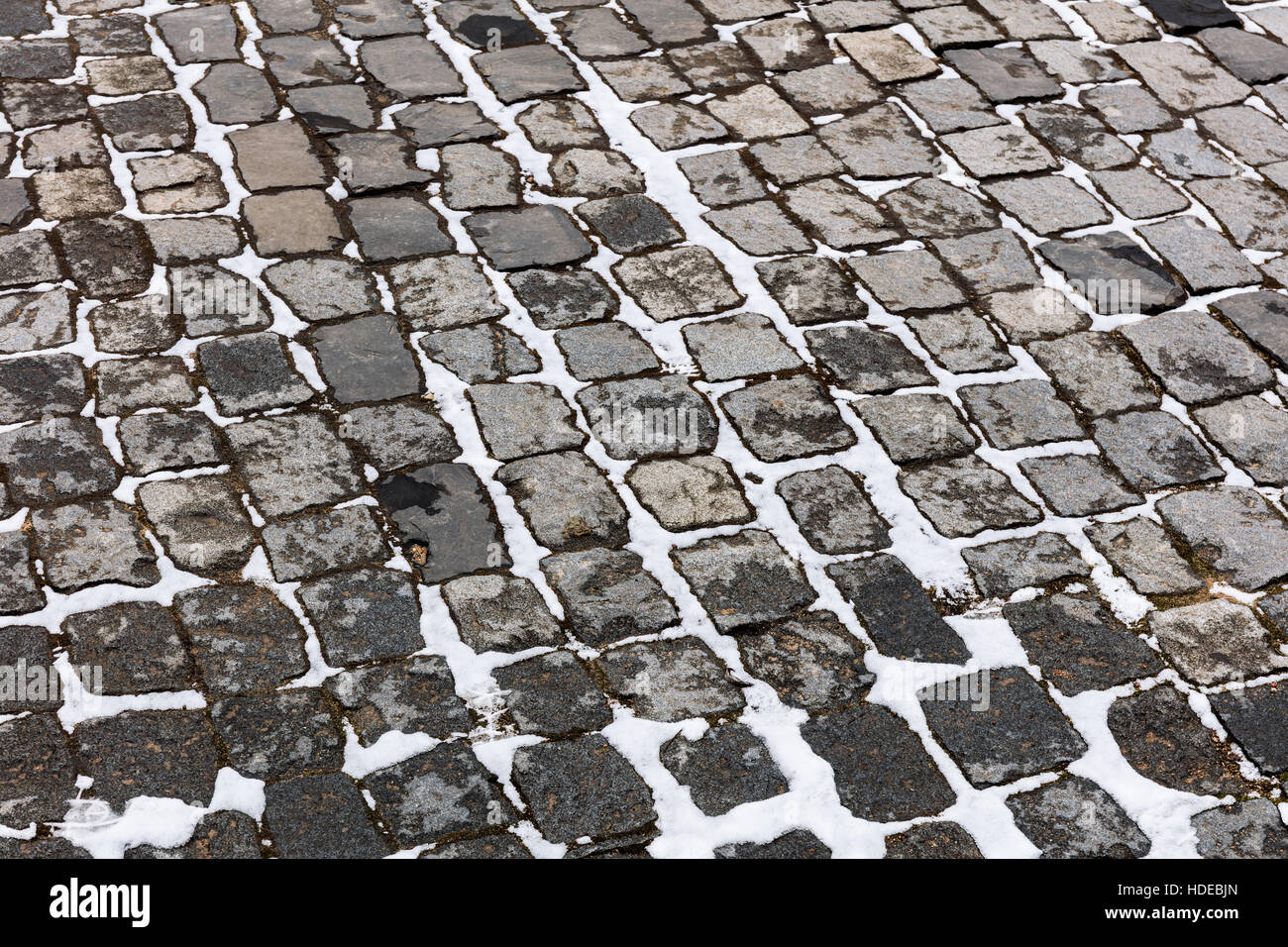 Kopfsteinpflaster Granit Bürgersteig Oberflächenmuster mit Schnee im winter Stockfoto